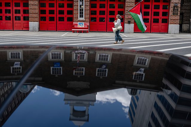 A demonstrator carrying a Palestinian flag walks in front of a fire station, Thursday, August 28, 2025, in Washington. (Photo by Jon Cherry/AP Photo)