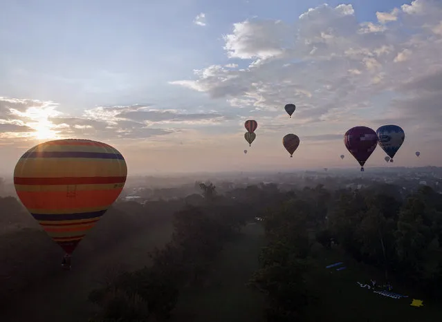 Hot air balloons fly over the sky in Chiang Mai province, northern Thailand, December 6, 2014. The two-day International Balloon festival 2014 featuring balloon pilots from Germany, Spain, Netherlands, Britain, and Czech Republic is held on December 06-07 2014 to celebrate Thai King Bhumibol Adulyadej's 87th birthday and also aimed to promote the tourism industry in Chiang Mai northern city. (Photo by Pongmanat Tasiri/EPA)