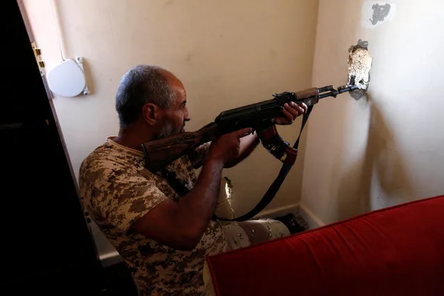 A fighter from Libyan forces allied with the U.N.-backed government aims his weapon through a hole in a wall as he looks for Islamic State militants in their remaining holdouts in Sirte, Libya, October 10, 2016. (Photo by Ismail Zitouny/Reuters)