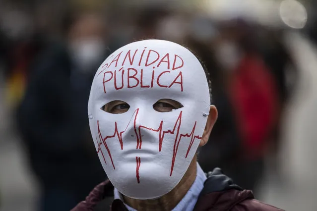 A demonstrator attends a protest to demand more resources for public health system in Madrid, Spain, Sunday, November 29, 2020. The organizers delivered a manifesto to the Madrid regional authorities demanding the end privatization of the health system. The mask reads in Spanish “Public health system”. (Photo by Bernat Armangue/AP Photo)