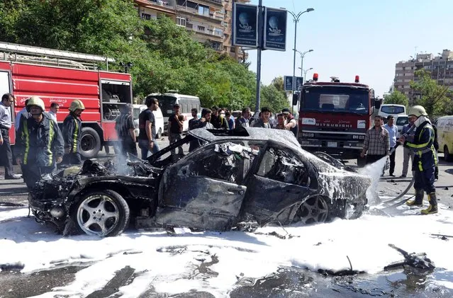 This photo released by the Syrian official news agency SANA, shows Syrian fire fighters extinguishing burning cars after a car bomb exploded in the capital's western neighborhood of Mazzeh, in Damascus, Syria, Monday, April. 29, 2013. State-run Syrian TV says the country's prime minister has escaped an assassination attempt when a bomb went off near his convoy. The TV says Prime Minister Wael al-Halqi was unhurt in the attack in the capital's western neighborhood of Mazzeh. (Photo by AP Photo/SANA)