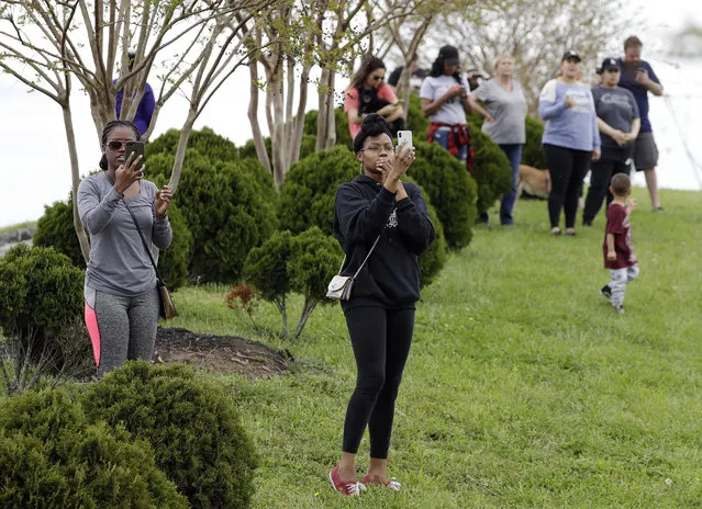 Residents of the apartment complex where Waffle House shooting suspect Travis Reinking lived watch as police work near the wooded area where Reinking was captured Monday, April 23, 2018, in Nashville, Tenn. Police say Reinking shot and killed at least four people at a nearby Waffle House restaurant Sunday. (Photo by Mark Humphrey/AP Photo)