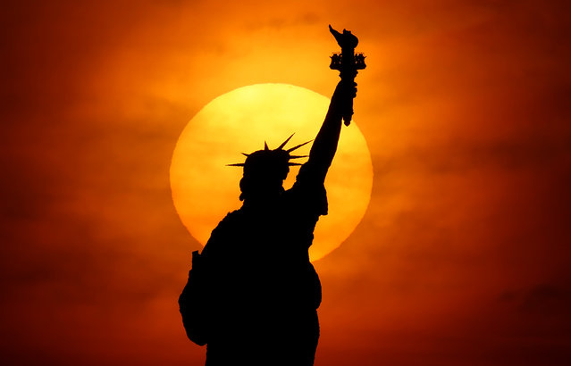 The sun rises behind the Statue of Liberty in New York City on October 19, 2025, as seen from Jersey City, New Jersey. (Photo by Gary Hershorn/Getty Images)