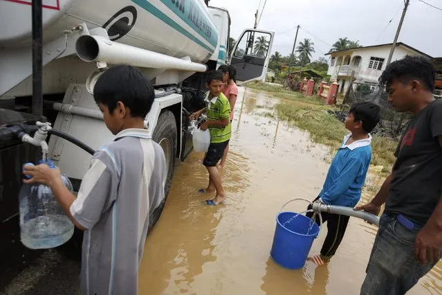 Residents fill containers with clean water at Pasir Mas in Kelantan December 29, 2014. (Photo by Athit Perawongmetha/Reuters)