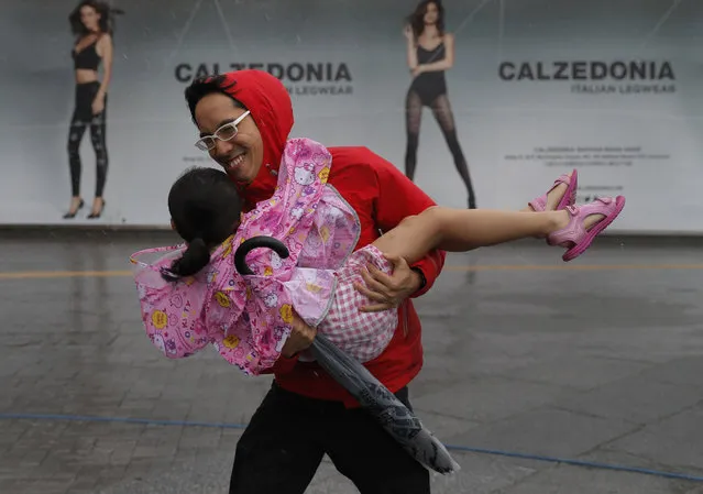 A man carries a girl brave the wind on the waterfront of Victoria Habour as Typhoon Haima approaches Hong Kong, Friday, October 21, 2016. (Photo by Vincent Yu/AP Photo)