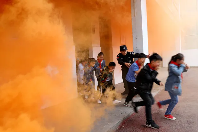 A police officer and schoolchildren take part in an anti-terrorism drill at a primary school in Huaibei, Anhui province, China May 7, 2018. (Photo by Reuters/China Stringer Network)
