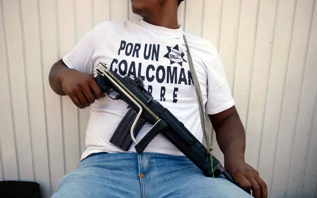 An armed man - member of a vigilante group – keeps watch in Coalcoman community, in Michoacan State, Mexico, on May 22, 2013. Vigilante groups, calling themselves “community police”, have sprung up this year in western and southern Mexican towns, in an effort to combat drug-related violence. (Photo by Alfredo Estrella/AFP Photo)