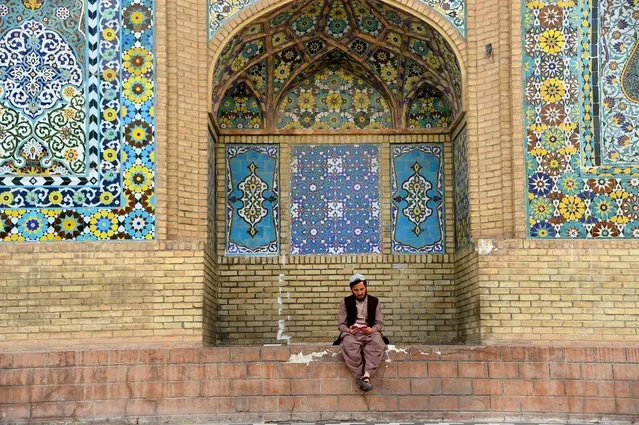 In this photo taken on June 2, 2018, an Afghan Muslim reads the Quran outside a mosque during the holy month of Ramadan in Herat Province. Muslims throughout the world are marking the month of Ramadan, the holiest month in the Islamic calendar during which Muslims fast from dawn until dusk. (Photo by Hoshang Hashimi/AFP Photo)