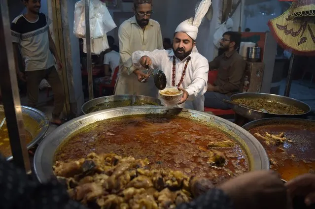 A Pakistani vendor prepares food for residents during sehri before beginning their Ramadan fast at Kartarpura “food street” in Rawalpindi on May 30, 2018. Muslims throughout the world are marking the month of Ramadan, the holiest month in the Islamic calendar during which Muslims fast from dawn until dusk. (Photo by Aamir Qureshi/AFP Photo)