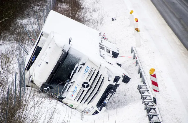 A truck is lying on its side in a ditch on the A2 motorway after an accident on a snowy and icy road in Wendeburg, Germany, Tuesday, February 9, 2021. (Photo by Hauke-Christian Dittrich/dpa via AP Photo)