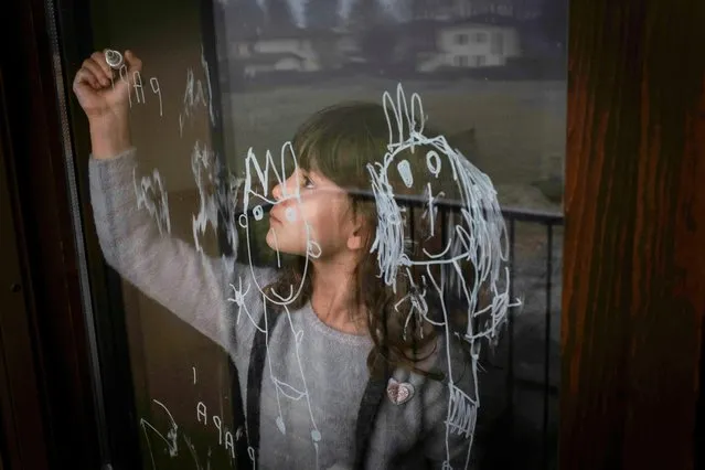 Bianca Toniolo draws on her bedroom's window on Christmas Eve in San Fiorano, Italy, December 24, 2020. Her father Marzio Toniolo has been documenting what life has been like for the small cluster of northern Italian towns since they were put on lockdown due to the coronavirus outbreak weeks before the rest of the country. (Photo by Marzio Toniolo/Reuters)
