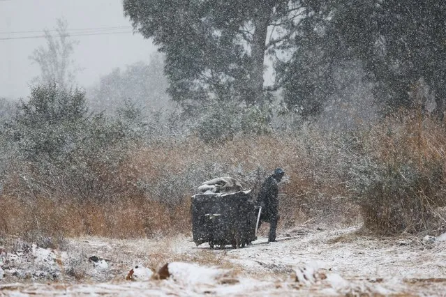 A garbage collector moves a trash bin amid snowfall in Brackenhurst, a suburb south of Johannesburg, South Africa on July 10, 2023. (Photo by Siphiwe Sibeko/Reuters)