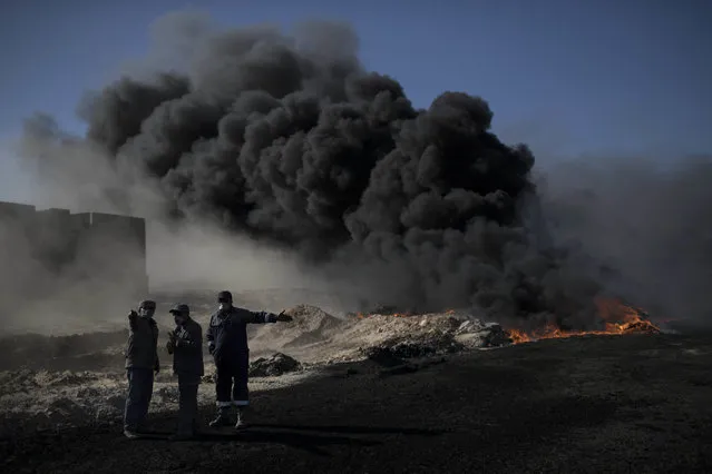 Oil workers try to extinguish burning oil fields in Qayara, south of Mosul, Iraq, Tuesday, November 22, 2016. (Photo by Felipe Dana/AP Photo)