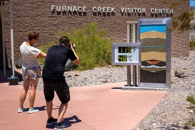People stop to take photos of a thermostat reading 119° Fahrenheit (48° Celsius) at the Furnace Creek visitor center on Tuesday, July 11, 2023, in Death Valley National Park, Calif. July is the hottest month at the park with an average high of 116 degrees (46.5 Celsius). (Photo by Ty ONeil/AP Photo)