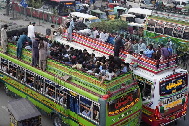 People travel on the rooftop of commuter buses to reach their towns and villagers ahead of Muslim Eid al-Adha, or Feast of Sacrifice holiday, in Lahore, Pakistan, Tuesday, June. 27, 2023. (Photo by K.M. Chaudary/AP Photo)