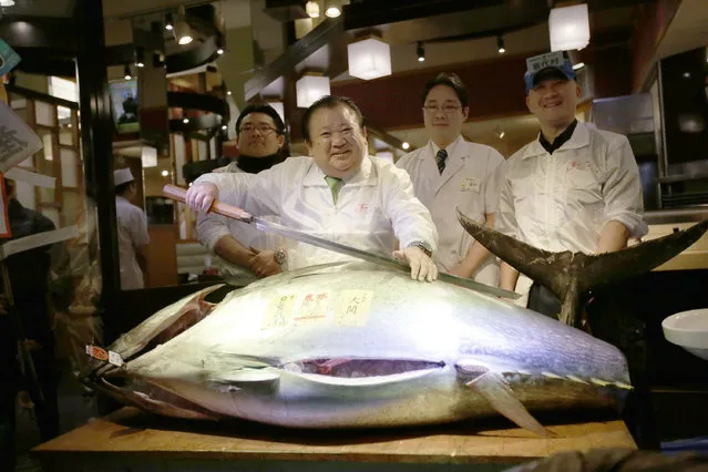 Kiyoshi Kimura, second from left, president of Kiyomura Co., poses a bluefin tuna at his Sushi Zanmai restaurant near Tsukiji fish market in Tokyo, Tuesday, January 5, 2016. (Photo by Eugene Hoshiko/AP Photo)