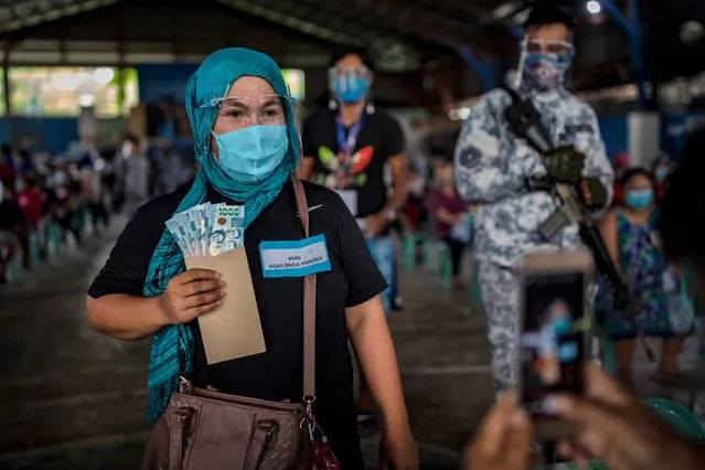 A social worker takes a picture of a resident receiving cash aid on April 7,2021 in Manila, Philippines. Each resident is entitled to 1,000 pesos ($20), with a limit of 4,000 pesos ($80) per household. Some 24 million people in Manila and nearby provinces remain under strict lockdown, the longest in the world, as the worst COVID-19 surge in Southeast Asia continues to hammer the country's healthcare system. The Philippines has confirmed more than 813,000 cases of COVID-19 so far, with nearly one in four people being tested turning out positive. (Photo by Ezra Acayan/Getty Images)