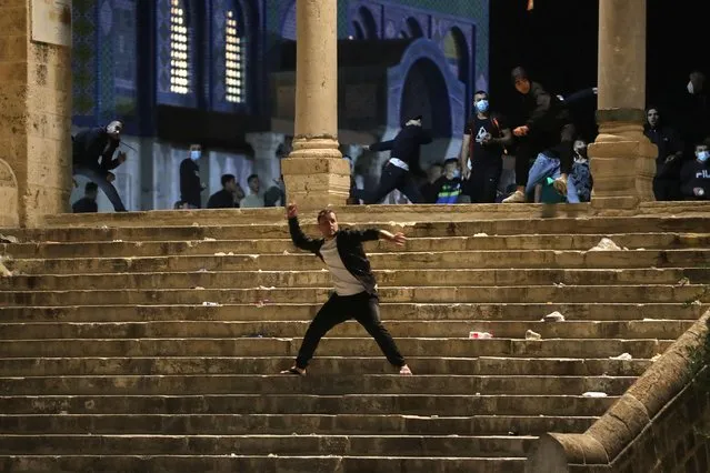 A Palestinian hurls stones at Israeli police during clashes at the compound that houses Al-Aqsa Mosque, known to Muslims as Noble Sanctuary and to Jews as Temple Mount, amid tension over the possible eviction of several Palestinian families from homes on land claimed by Jewish settlers in the Sheikh Jarrah neighborhood, in Jerusalem's Old City, May 7, 2021. (Photo by Ammar Awad/Reuters)