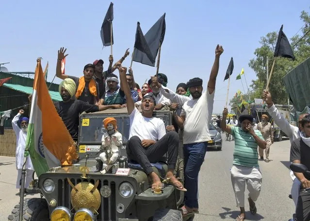 Farmers, some carrying black flags, on a vehicle during a protest in Ghazipur, outskirts of New Delhi, India, Wednesday, May 26, 2021. Indian farmers demanding the government repeal new agriculture laws they say will devastate their livelihoods marked their protest movement's sixth month Wednesday by flying black banners on the cars and tractors and burning effigies of the prime minister. (Photo by Ishant Chauhan/AP Photo)