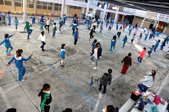 Children stretch before entering their classrooms at the Ignacio Zaragoza elementary school as Mexico City's authorities resumed in-person classes today after a downward trend in the number of infections and hospitalisations of the coronavirus disease (COVID-19), in Mexico City, Mexico on June 7, 2021. (Photo by Luis Cortes/Reuters)