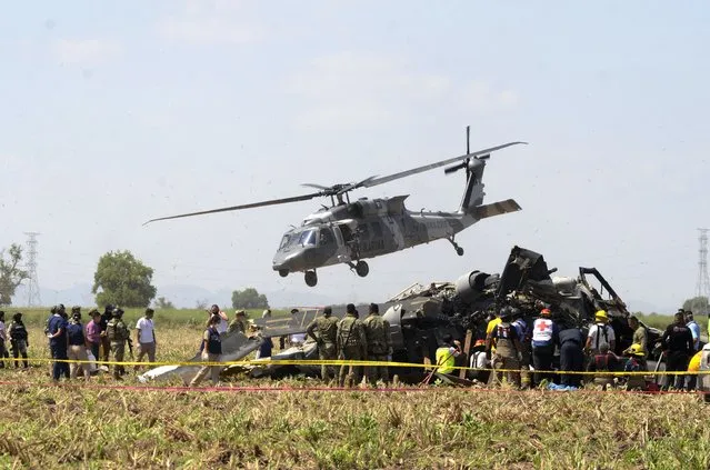 Emergency personnel work next to a navy Blackhawk helicopter crashed after supporting those who conducted the capture of drug lord Rafael Caro Quintero, near Los Mochis, Sinaloa state, Mexico, Friday, July 15, 2022. Mexico's navy said multiple people aboard died. (Photo by Guillermo Juarez/AP Photo)