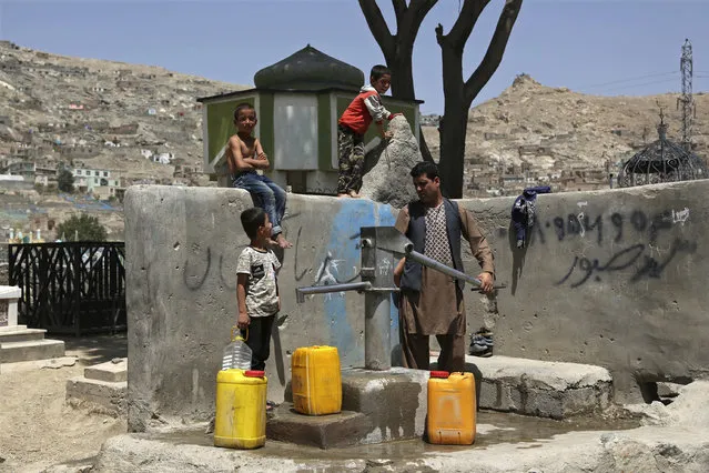 A man and his children collect water from a public water pump in Kabul, Afghanistan, Monday, July 30, 2018. (Photo by Rahmat Gul/AP Photo)
