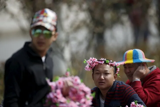 A man wearing flowers on his head is seen at a park in Shanghai March 24, 2015. (Photo by Aly Song/Reuters)