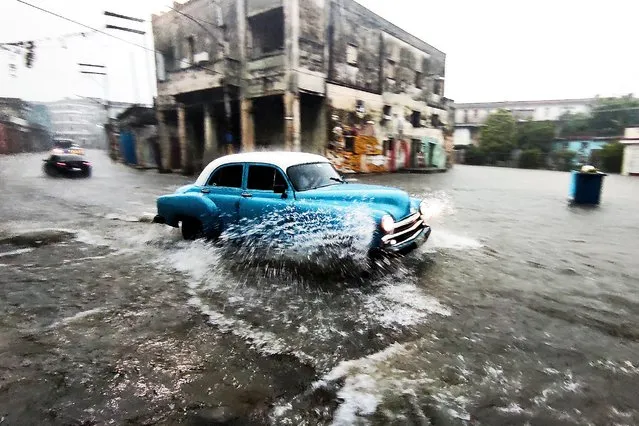 An Old American car drives through a flooded street in Havana, on June 30, 2021. Heavy rains and malfunctioning sewers cause the flooding of streets in Havana. (Photo by Yamil Lage/AFP Photo)