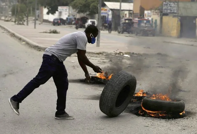 A supporter of former Senator Youri Latortue and Steven Benoit sets fire to tires outside of Haiti's courthouse in Port-au-Prince, Monday, July 12, 2021. Prosecutors have requested that high-profile politicians like Latortue and Benoit meet officials for questioning as part of the investigation into the assassination of President Jovenel Moise. (Photo by Joseph Odelyn/AP Photo)