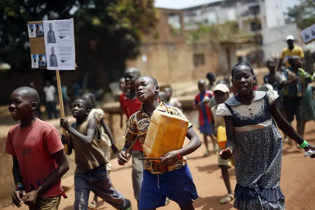 Children walk holding political placards in Bangui, Central African Republic,  Wednesday February 10, 2016. Two former prime ministers, Faustin Archange Touadera and Anicet Georges Dologuele, are running neck-and-neck in the second round of presidential elections Sunday Feb. 14 to end years of violence pitting Muslims against Christians in the Central African Republic. (Photo by Jerome Delay/AP Photo)