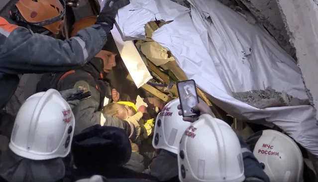 This photo provided by the Russian Emergency Situations Ministry taken from tv footage shows Emergency Situations employees save a 10 month old baby at the scene of a collapsed section of an apartment building, in Magnitigorsk, a city of 400,000 about 1,400 kilometers (870 miles) southeast of Moscow, Russia, Tuesday, January 1, 2019. Rescue crews on Tuesday temporarily halted their search through the rubble in the city of Magnitogorsk while workers tried to remove or stabilize sections of the building in danger of collapse. (Photo by Russian Ministry for Emergency Situations via AP Photo)