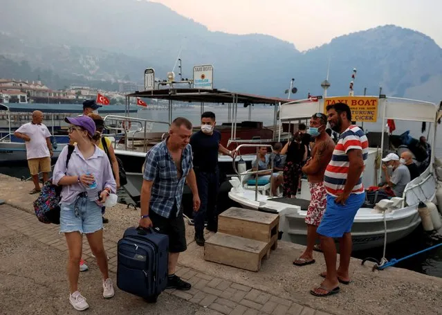 Tourists board a boat during evacuation as a wildfire approaches Turunc village, near Marmaris, Turkey, August 1, 2021. (Photo by Umit Bektas/Reuters)