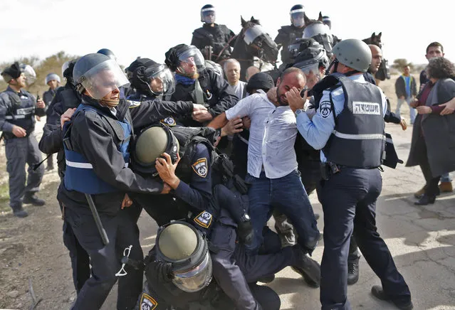 Israeli policemen detain a Bedouin man during clashes that followed a protest against home demolitions on January 18, 2017 in the Bedouin village of Umm al- Hiran, which is not recognized by the Israeli government, near the southern city of Beersheba, in the Negev desert An Israeli policeman was killed while taking part in an operation to demolish homes in the Bedouin village, with authorities claiming he was targeted in a car- ramming attack. The driver was earlier reported shot dead by police as residents disputed the police version of events, saying the driver was heading to the scene to talk with authorities in an attempt to halt the demolitions. (Photo by Ahmad Gharabli/AFP Photo)