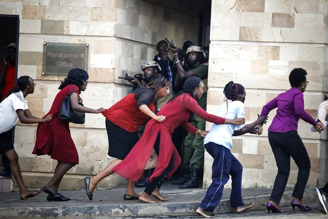 Women are evacuated out of the scene as security officers search for attackers during an ongoing gunfire and explosions in Nairobi, Kenya, 15 January 2019. According to reports, a large explosion and sustained gunfire sent workers fleeing for their lives at an upscale hotel and office complex in the Kenyan capital of Nairobi. (Photo by Dai Kurokawa/EPA/EFE)