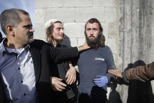 Palestinians hold injured Israeli settlers detained by Palestinian villagers in a building under construction near the West Bank village of Qusra, southeast of the city of Nablus, Tuesday, January 7, 2014. (Photo by Nasser Ishtayeh/AP Photo)