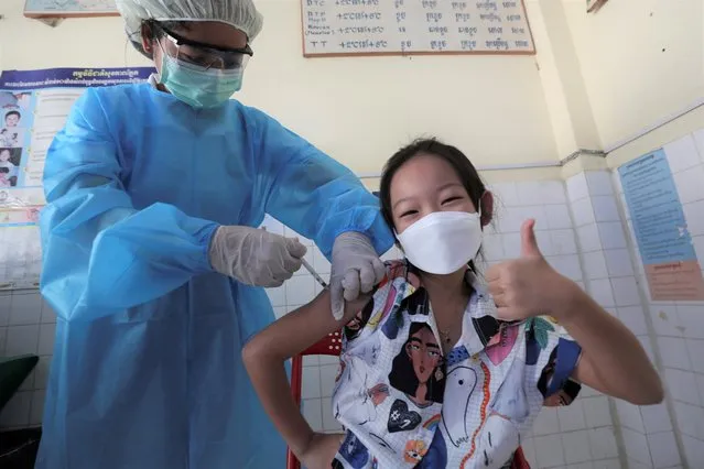 A young girl thumbs up as she receives a shot of the Sinovac's COVID-19 vaccine at a Samrong Krom health center outside Phnom Penh, Cambodia, Friday, September 17, 2021. Prime Minister Hun Sen announced the start of a nationwide campaign to give COVID-19 vaccinations to children between the ages of 6 and 11 so they can return to school safely after a long absence due to measures taken against the spread of the coronavirus. (Photo by Heng Sinith/AP Photo)