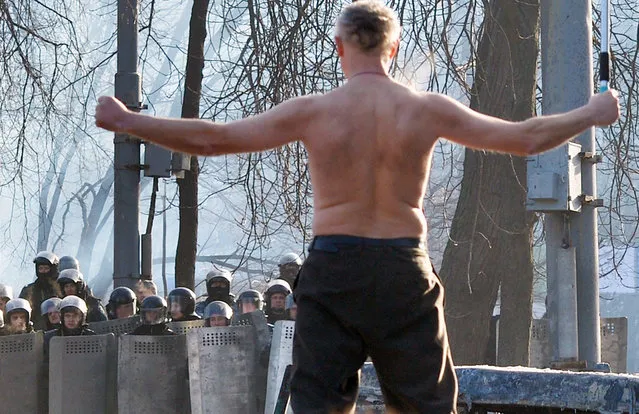 A bare chested man waves a Ukrainian flag during clashes between the opposition and police in Kiev, on January 20, 2014. (Photo by Sergei Supinsky/AFP Photo)