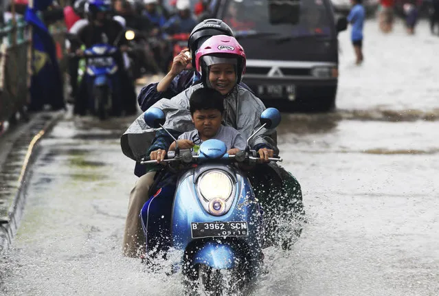 A woman reacts as she rides a motorcycle through a flooded street in Jakarta, January 24, 2014. Torrential rains that have continued in Jakarta in recent days widened the number of flooded areas caused more than 10,000 houses have been flooded with 64,000 people being displaced from their homes, a local newspaper said on Thursday. (Photo by Reuters/Beawiharta)
