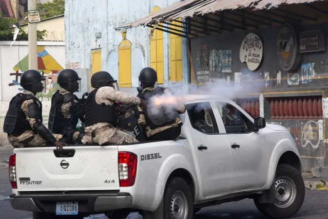 A National Police officer fires tear gas at protesters who are demanding the resignation of Haitian President Jovenel Moise near the presidential palace in Port-au-Prince, Haiti, Tuesday, February 12, 2019. Protesters are angry about skyrocketing inflation and the government's failure to prosecute embezzlement from a multi-billion Venezuelan program that sent discounted oil to Haiti. (Photo by Dieu Nalio Chery/AP Photo)