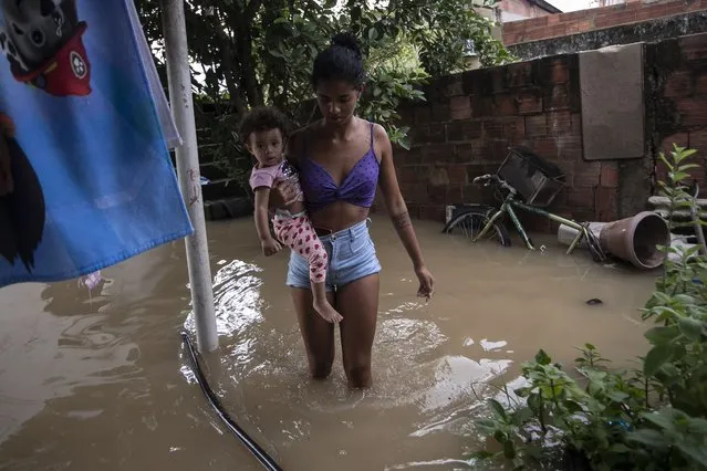 Ingrid Monteiro carries her one-year-old daughter Aylla Perola over floodwaters outside their home after deadly, heavy rainfall in Duque de Caxias, Brazil, Sunday, January 14, 2024. (Photo by Bruna Prado/AP Photo)