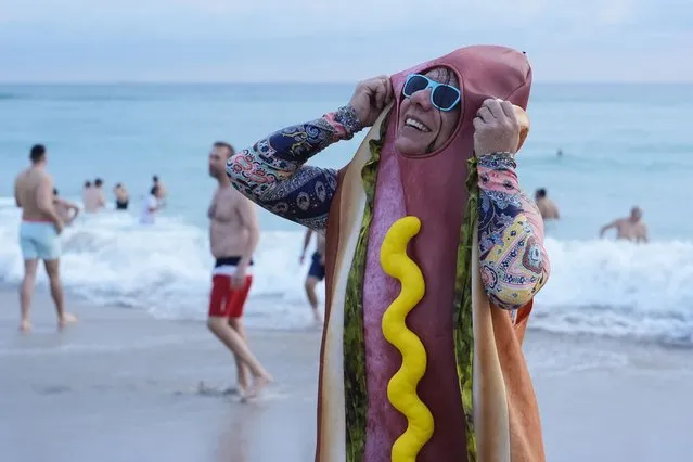 Christina Lusk of Fort Lauderdale adjusts her wet hotdog costume as she emerges from the ocean during a Groundhog Day celebration in Hollywood, Fla., just after dawn on Friday, February 2, 2024. Hollywood's version of Punxsutawney Phil saw his shadow and predicted “six more weeks of tourism” for the area, before dozens of celebrants sang the national anthem then ran into the ocean as part of a local Groundhog Day tradition that dates back twenty years. (Photo by Rebecca Blackwell/AP Photo)