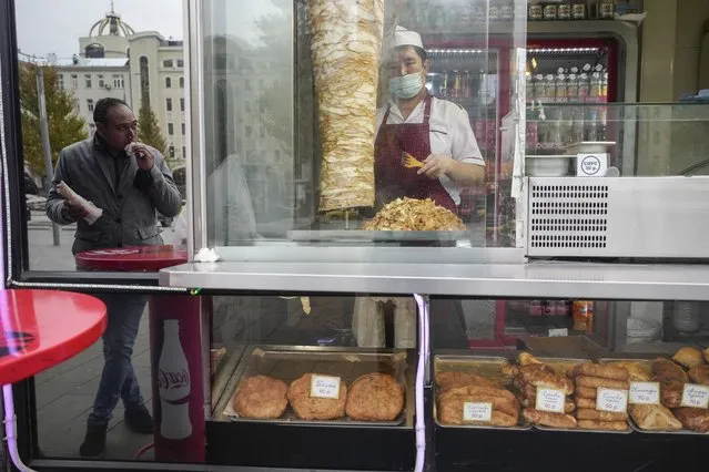 A cook cuts doner kebab for take-away in Moscow, Russia, Friday, October 29, 2021. Russia has recorded another record of daily coronavirus deaths even as authorities hope to stem contagion by keeping most people off work. Moscow introduced the measure starting from Thursday, shutting kindergartens, schools, gyms, entertainment venues and most stores, and restricting restaurants and cafes to only takeout or delivery. Food stores, pharmacies and companies operating key infrastructure remained open. (Photo by Pavel Golovkin/AP Photo)