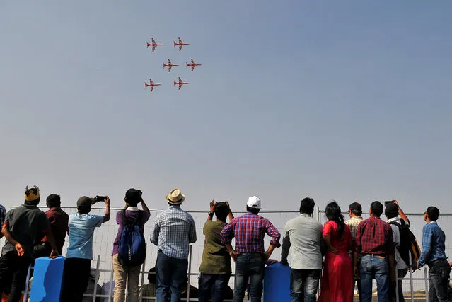 People watch the Indian Air Force's “Suryakiran” jet trainers perform during the Aero India show at the Yelahanka Air Force Station in Bengaluru, India February 17, 2017. (Photo by Abhishek N. Chinnappa/Reuters)