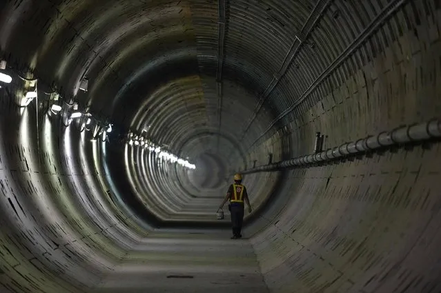 This picture taken on March 8, 2016 shows a worker walking in a tunnel under construction along the current extension of the Metropolitan Rapid Transit (MRT) subway “Blue Line” into Bangkok's historic district of Chinatown. The Blue Line is the MRT's only line currently in operation, running from the central Hua Lamphong train station to the north of Bangkok and was opened in 2004 as Bangkok's second public transit system. The MRT serves hundreds of thousands of passengers each day, allowing them to escape the city's famously-chaotic traffic, and currently has 18 operational stations along 20 kilometers of underground route. (Photo by Christophe Archambault/AFP Photo)