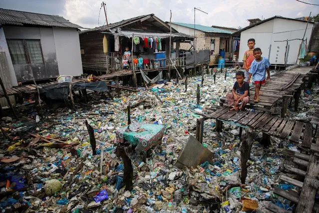 Boys play near rubbish, most of which are plastics, in the coastal settlements of Tanjung Uma, Batam, Riau Islands province, Indonesia on November 15, 2021. (Photo by Teguh Prihatna/Antara Foto via Reuters)