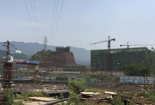 A nail house (centre L) sits atop a mound, next to a construction site for a new residential area, in Yibin, Sichuan province, China, May 19, 2015. (Photo by Reuters/Stringer)