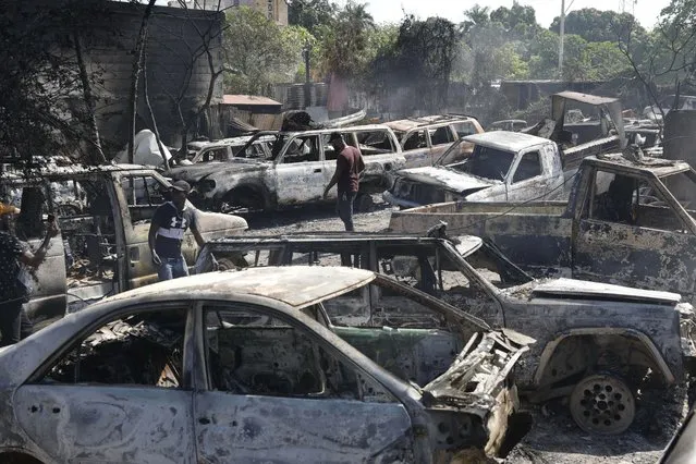 People look for salvageable pieces from burned cars at a mechanic shop that was set on fire during violence by armed gangs in Port-au-Prince, Haiti, Monday, March 25, 2024. (Photo by Odelyn Joseph/AP Photo)