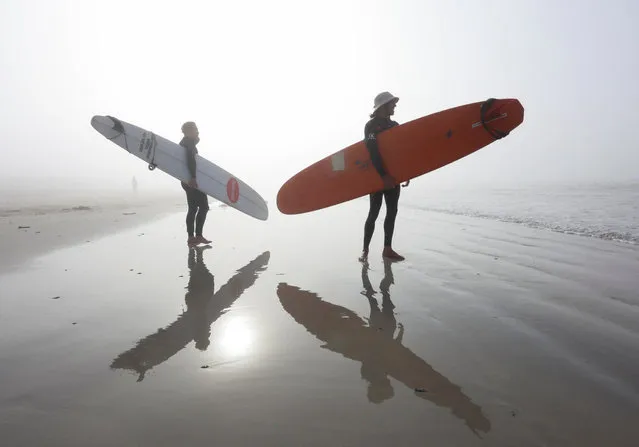 Surfers stand on Muizenberg beach in the early morning as seasonal mist shrouds the sun in Cape Town, South Africa, on April 18, 224. (Photo by Esa Alexander/Reuters)