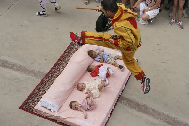 The “Colacho”, a character that represents the devil, jumps over babies lying on a mattress in the street during “El Salto del Colacho” (The Devil's Jump) baby jumping festival, in the village of Castrillo de Murcia, near Burgos, on June 23, 2019. “El Colacho” is a traditional Spanish ritual dating back to 1620 during which men representing the Devil jump over babies born in the last twelve months of the year and takes place annually to celebrate the Catholic feast of Corpus Christi. (Photo by Cesar Manso/AFP Photo)