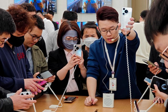 People try Huawei's latest Pura 70 series phone at a store in Shanghai on April 18, 2024. (Photo by AFP Photo/China Stringer Network)